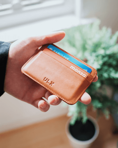 hand holding leather wallet with credit card