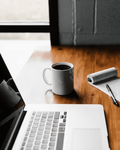 Laptop, cup of cofee, and a pen and notepad